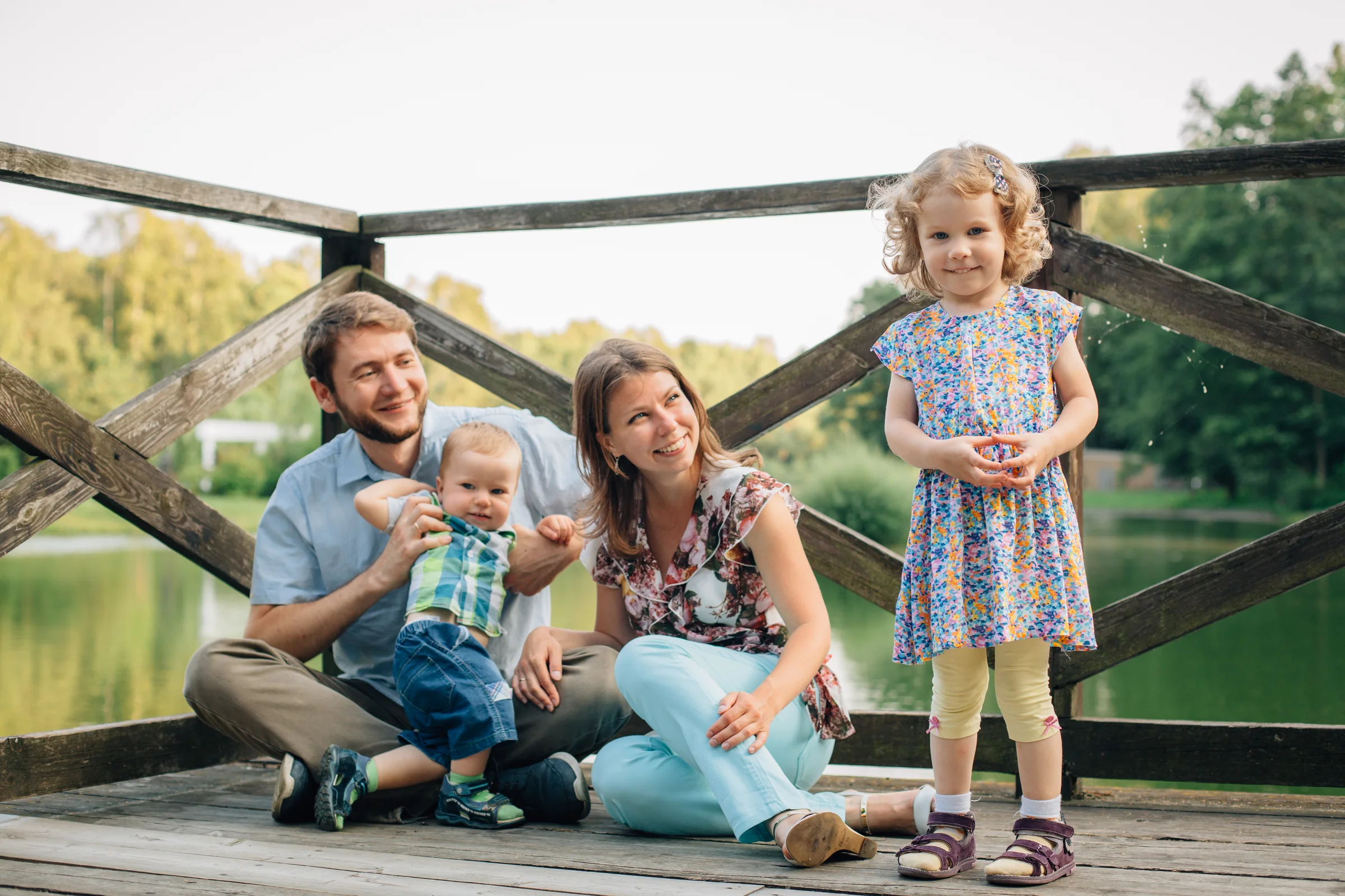 Parents and their two children together on a wooden bridge by the water